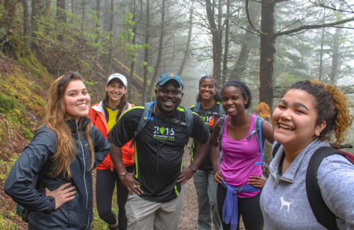 Cassius Cash and a group of young people smiling for a photo on a nature walk in the forest